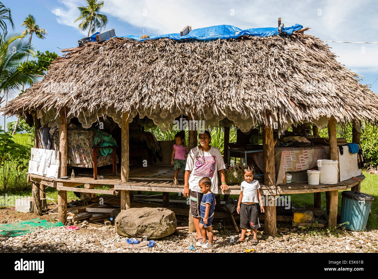 Samoan family standing in front of their typical polynesian style house