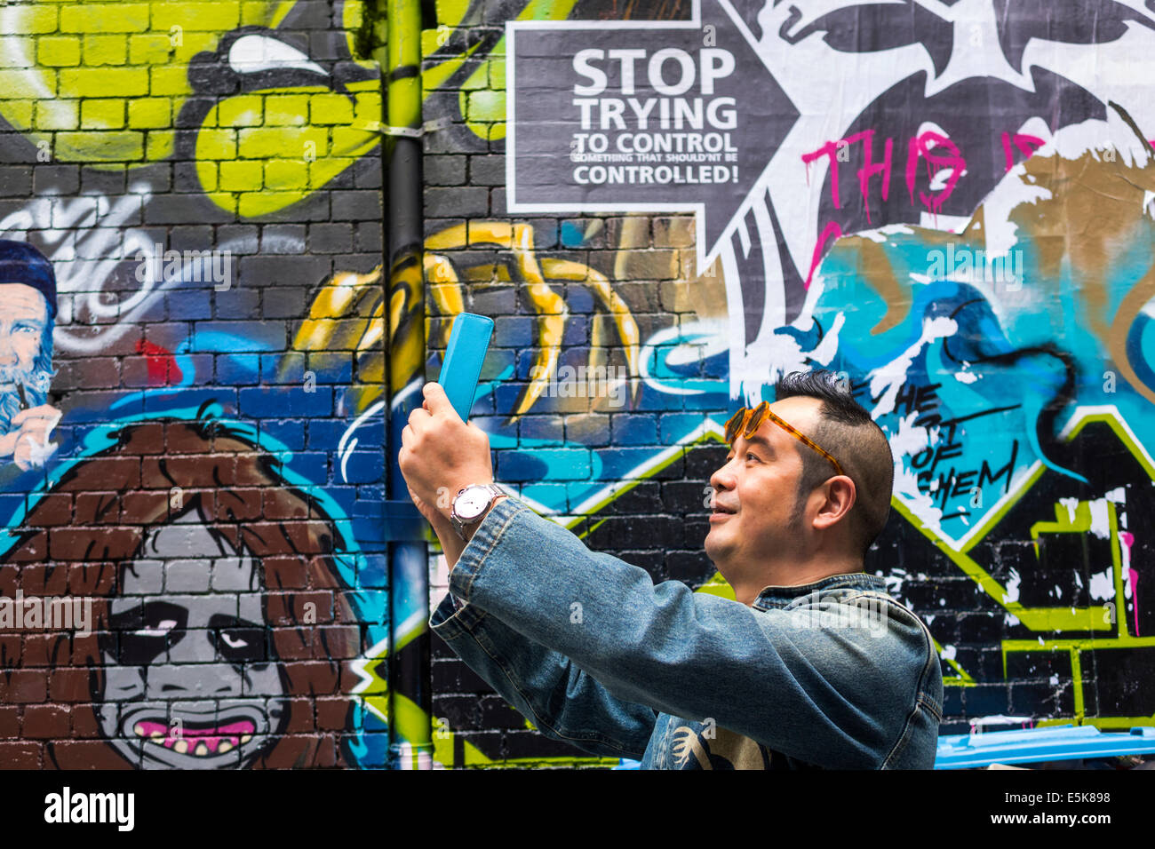 Melbourne Australia,Hosier Lane,urban street art,murals,graffiti,Asian man men male,tablet,iPad,taking,AU140322068 Stock Photo