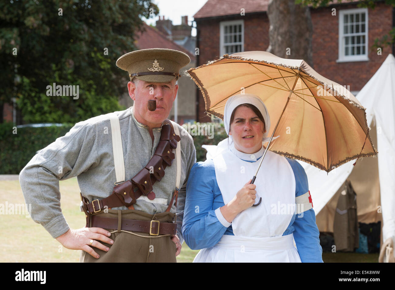 Chichester West Sussex UK, 3rd August 2014. A drumhead service was held in Priory Park Chichester to mark the centenary of the first world war ( 4 August ) with the public, ex servicemen and servicemen and re-enactment group attending, , image showing a re-enactment of a WW1 serviceman smoking a pipe and a nurse holding a umbrella parasol  Credit: Photovision Images / Alamy Live News Stock Photo