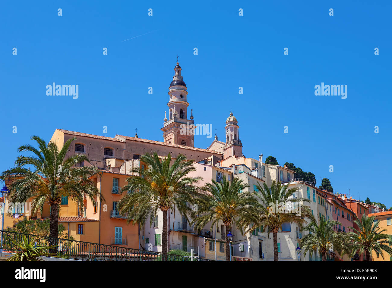 Bell tower among colorful houses under blue sky in Menton, France. Stock Photo