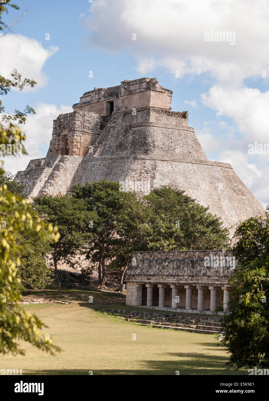 Uxmal's Mayan Pyramid of the Magician rises well above the surrounding trees. The massive stone structure rises majestically Stock Photo