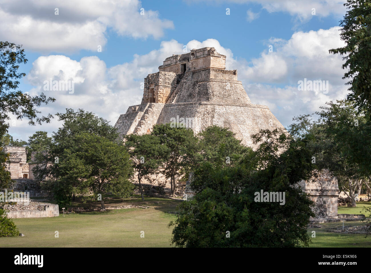 Uxmal's Mayan Pyramid of the Magician rises above the trees. The massive stone structure rises majestically dominating. Stock Photo