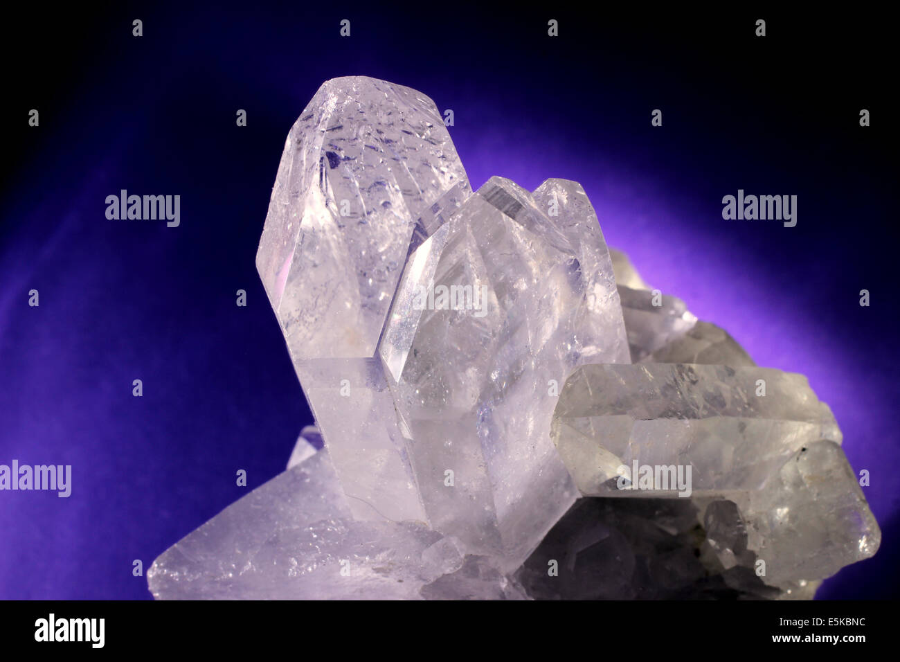 Quartz crystal illuminated with purple glowing background Stock Photo