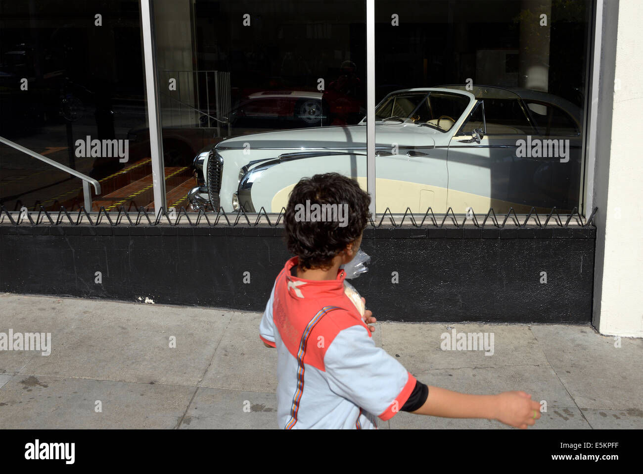 san francisco boy walks past classic car in showroom Stock Photo