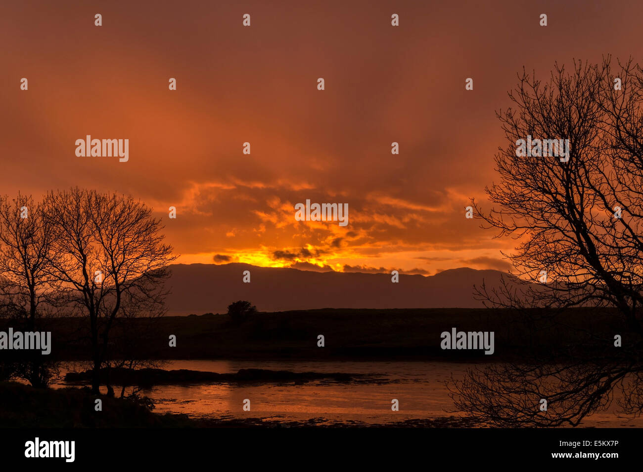 Orange fiery sunset over the Red Cuillin mountains and waters of Broadford Bay, Lower Breakish, Isle of Skye, Scotland, UK. Stock Photo