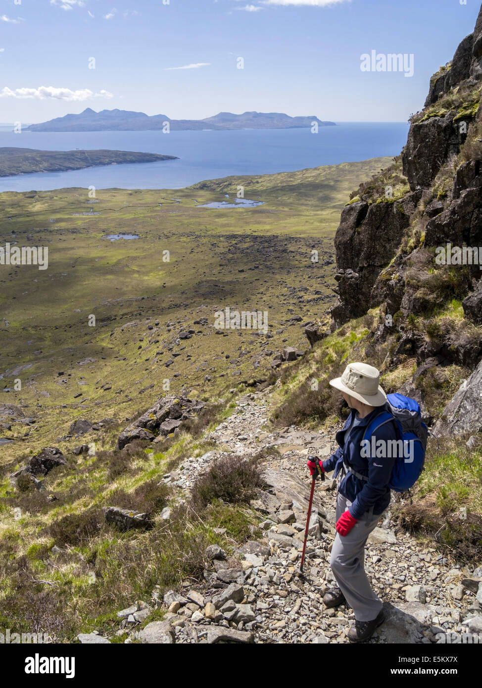 Lone female hill walker high on ascent to Coir a Ghrunnda in Cuillin mountains with Isle of Rum in distance, Skye,Scotland, UK Stock Photo