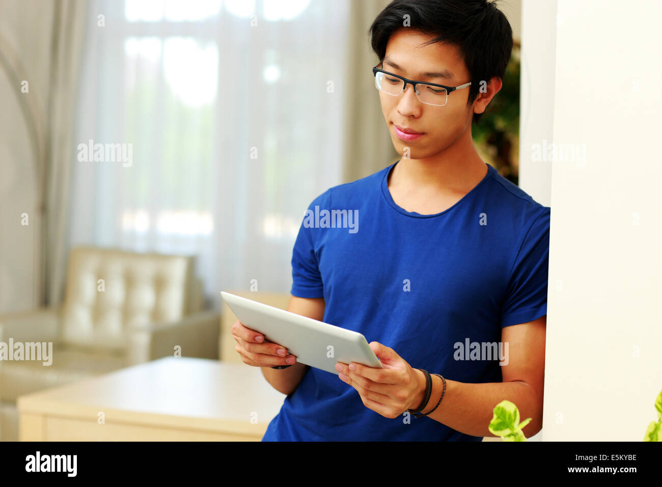 Serious asian man using tablet computer at home Stock Photo