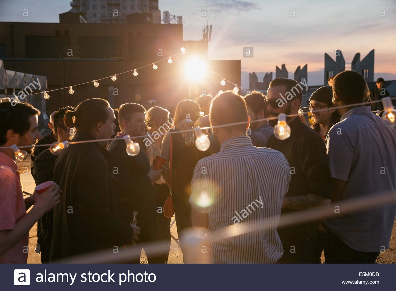 String lights over crowd at rooftop party Stock Photo