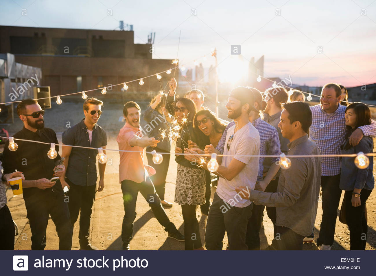 Friends with sparklers enjoying urban rooftop party Stock Photo