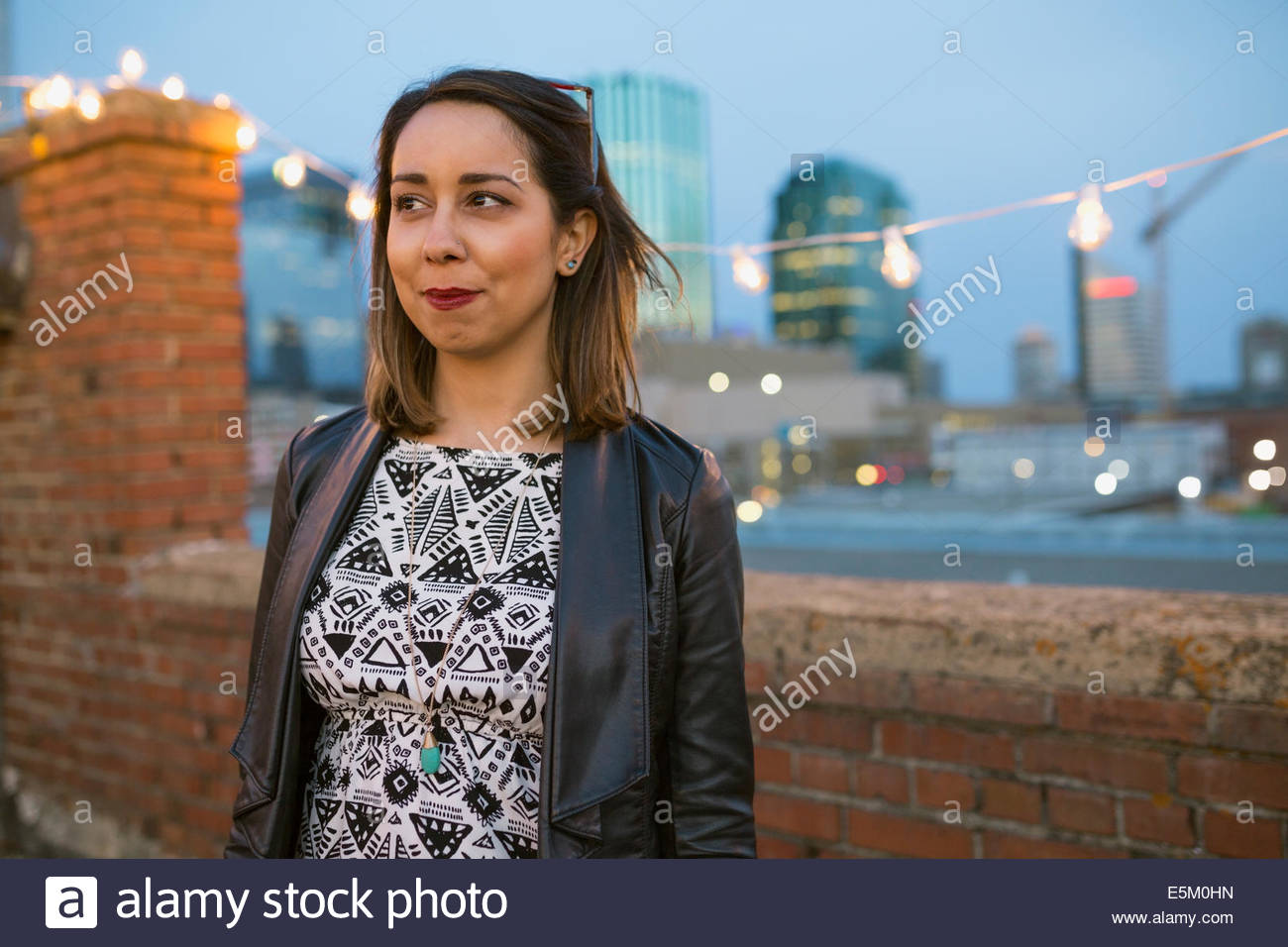 Smiling woman looking away on urban rooftop Stock Photo