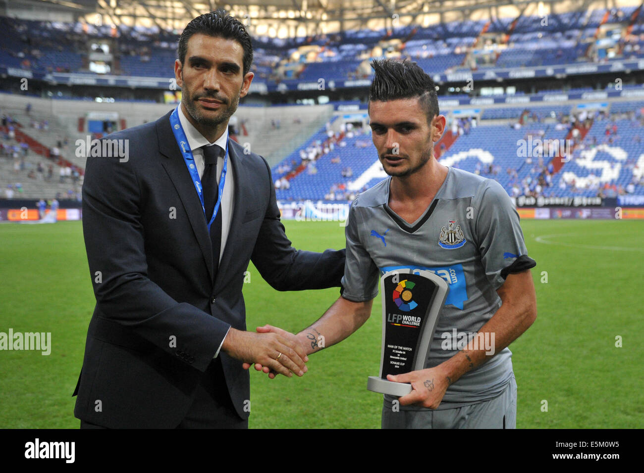 Gelsenkirchen, Germany. 03rd Aug, 2014. Fernando Sanz (L), ambassador of the 'Liga de Futbol Profesional' LFP, gives the trophy for the second place in the Schalke Cup to Newcastle's Remy Cabella after the Schalke Cup test match between FC Schalke 04 and Newcastle United at Veltins-Arena in Gelsenkirchen, Germany, 03 August 2014. Photo: Matthias Balk/dpa/Alamy Live News Stock Photo