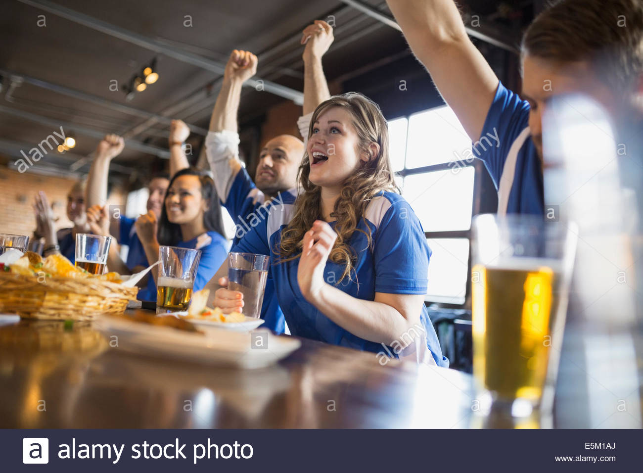 Sports fans cheering at bar in pub Stock Photo