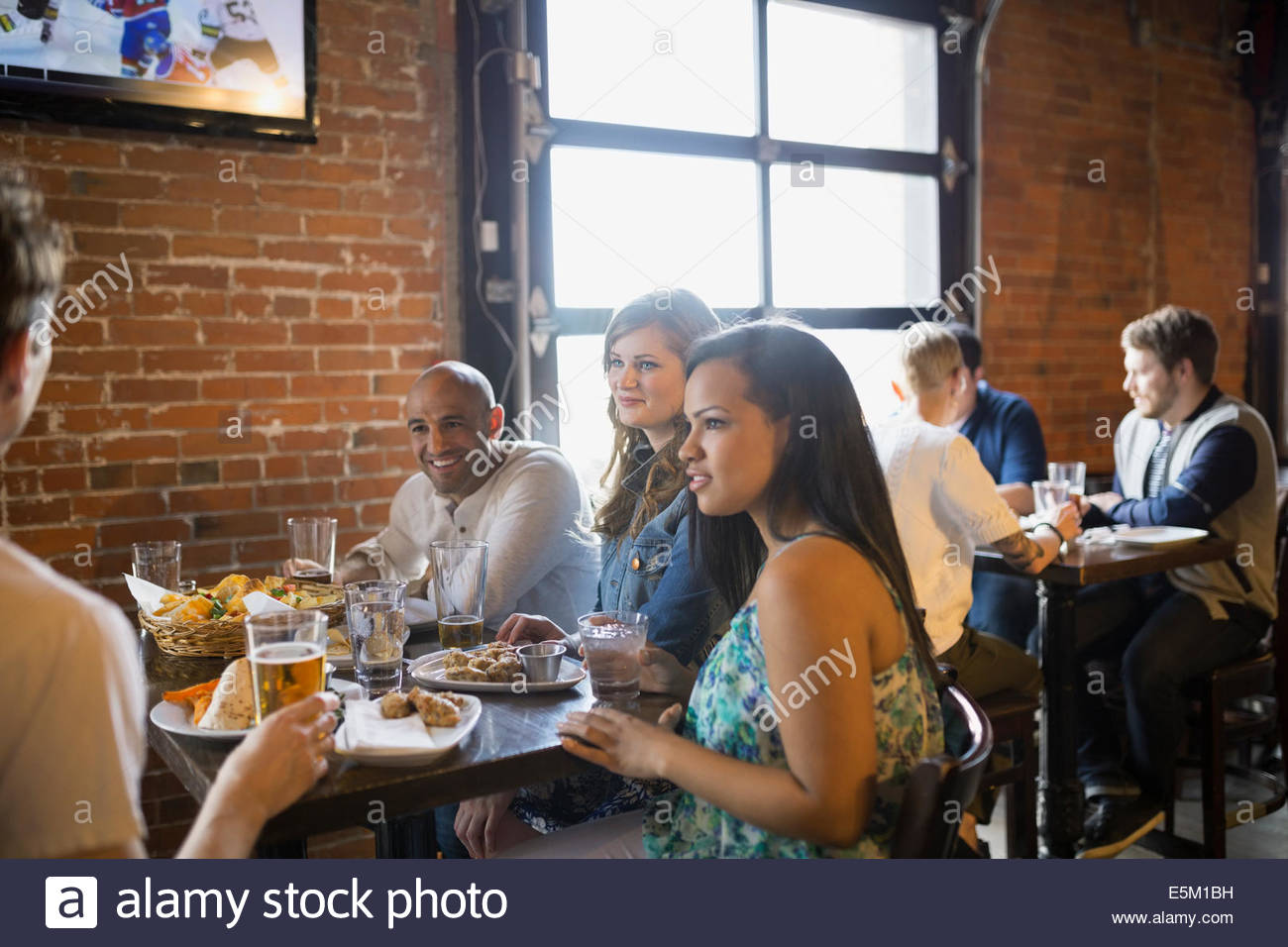 Friends talking and eating in pub Stock Photo