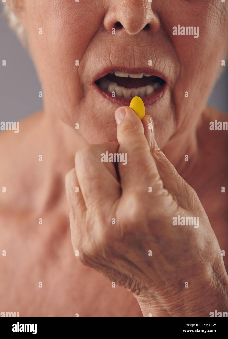 Cropped image of old woman taking a pill. Focus on hand and pill. Close-up of senior woman taking medication for good health. Stock Photo