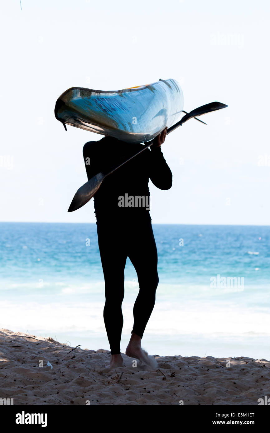 Man with kayak and paddle walking down to the ocean in Australia Stock ...