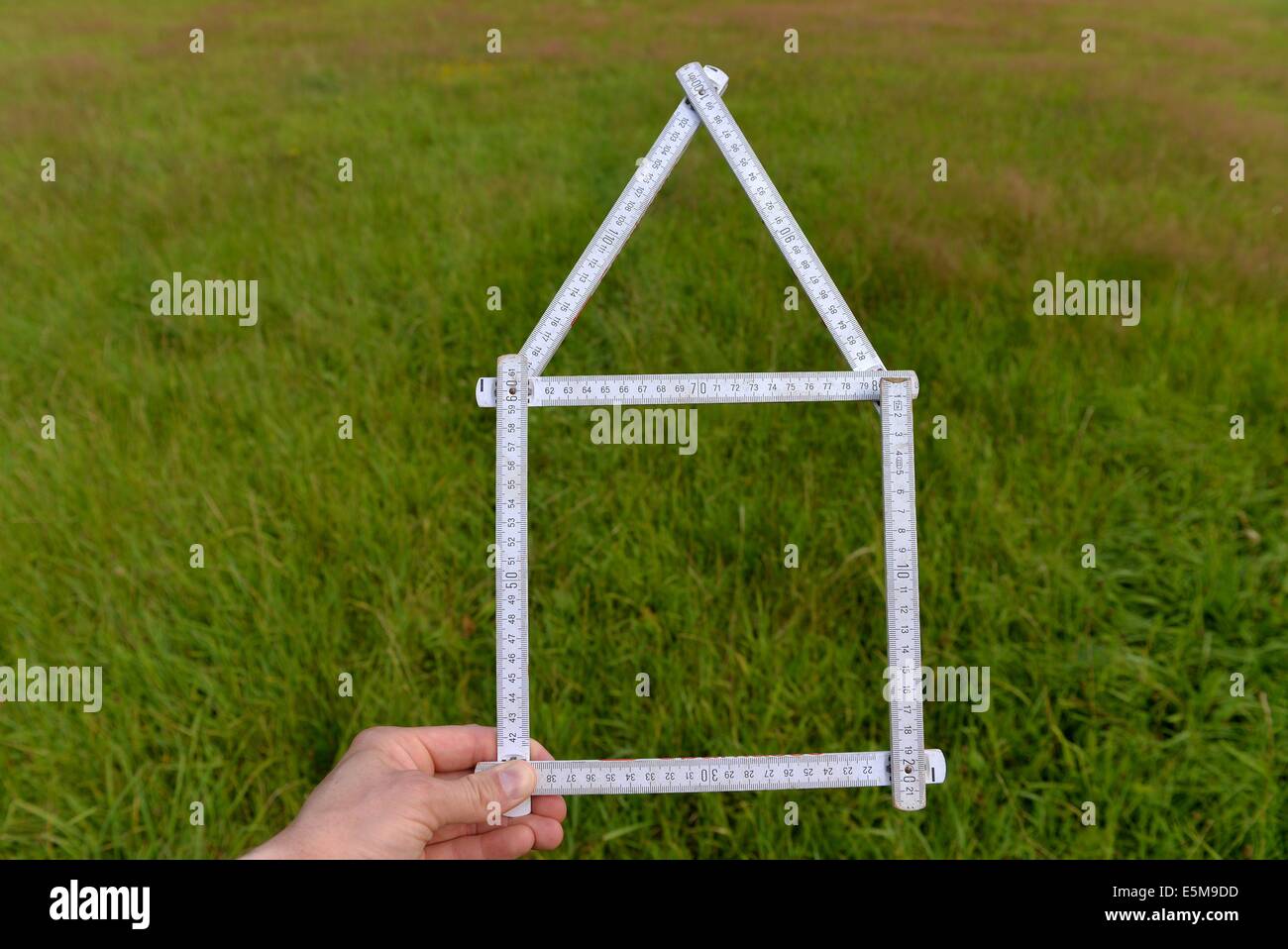 A folding rule in the shape of an house, held into the landscape