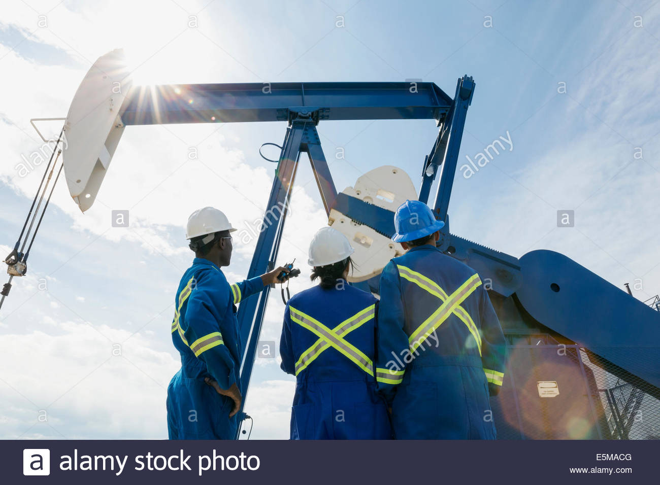 Workers looking up at oil well Stock Photo