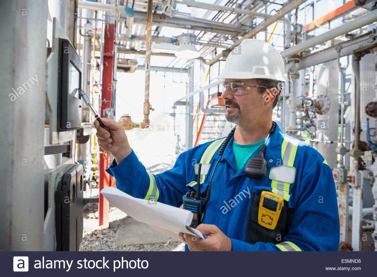 Male worker checking equipment at gas plant Stock Photo