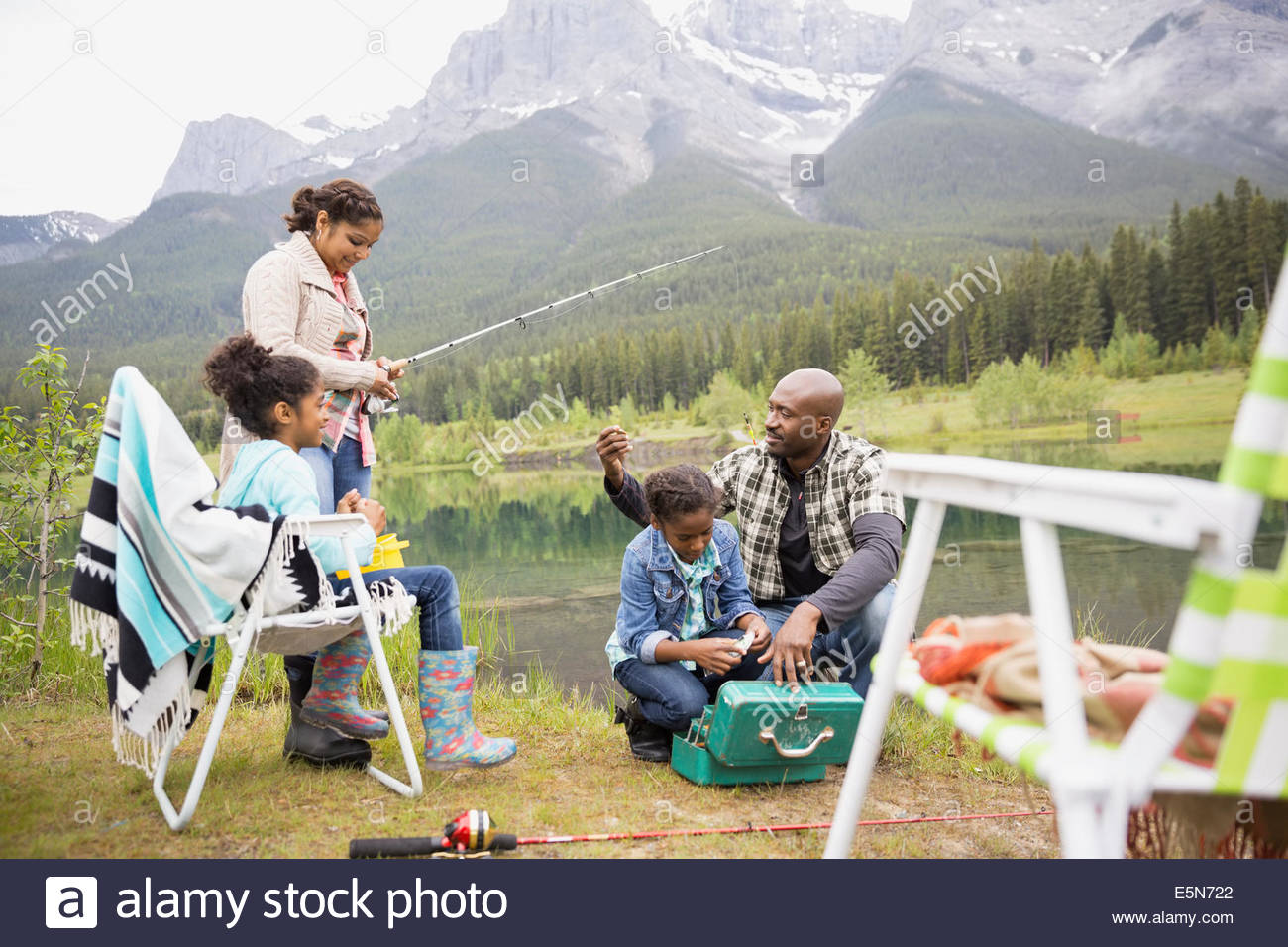 Family preparing to fish at lakeside below mountains Stock Photo