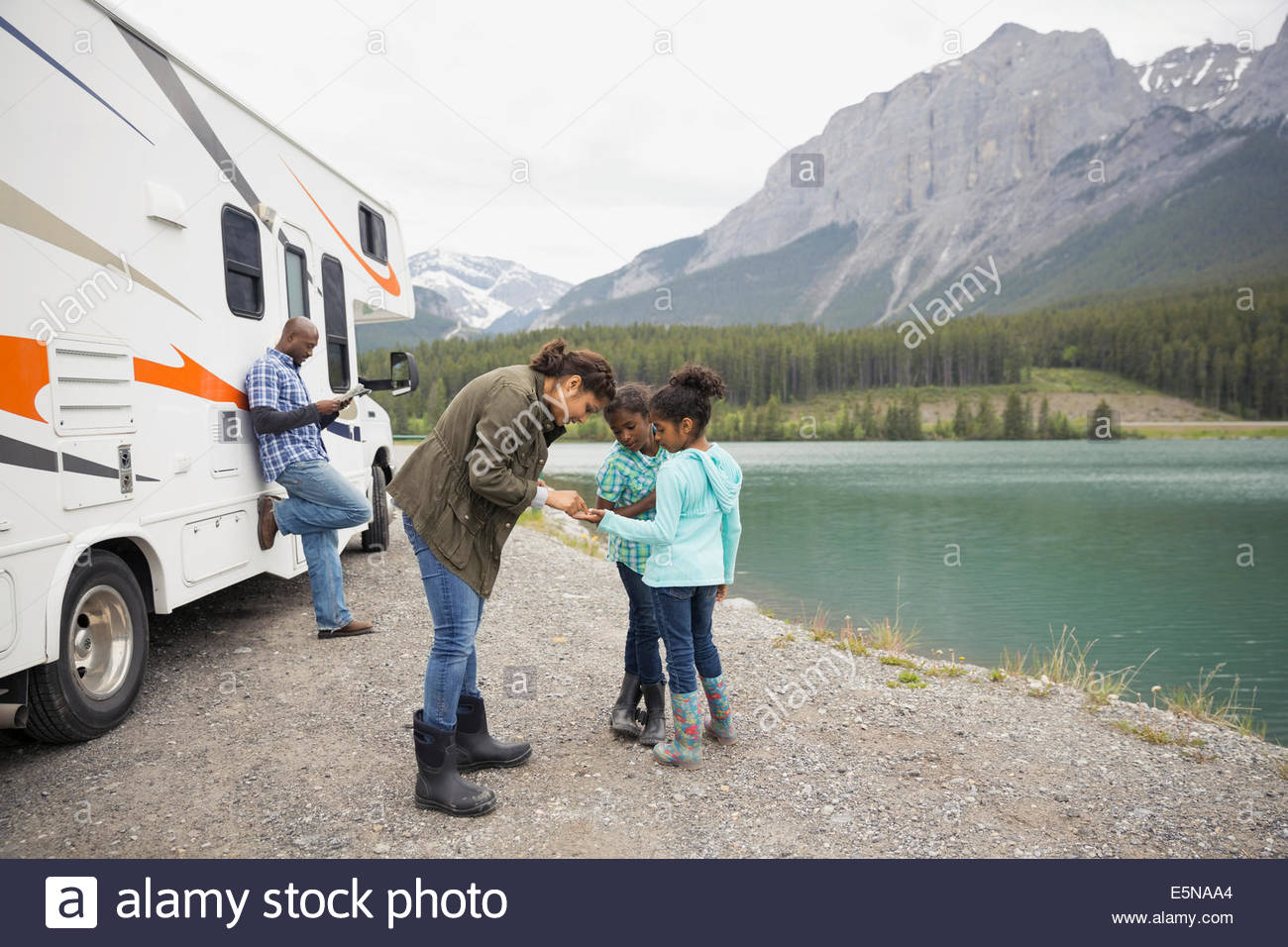 Family standing at lakeside near RV Stock Photo
