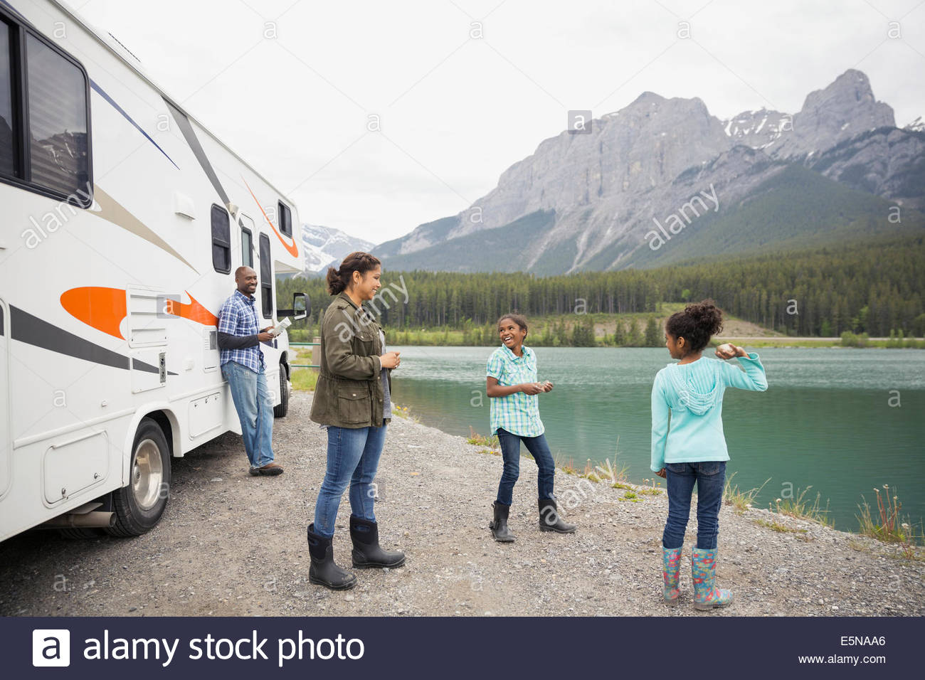Family standing at lakeside near RV Stock Photo
