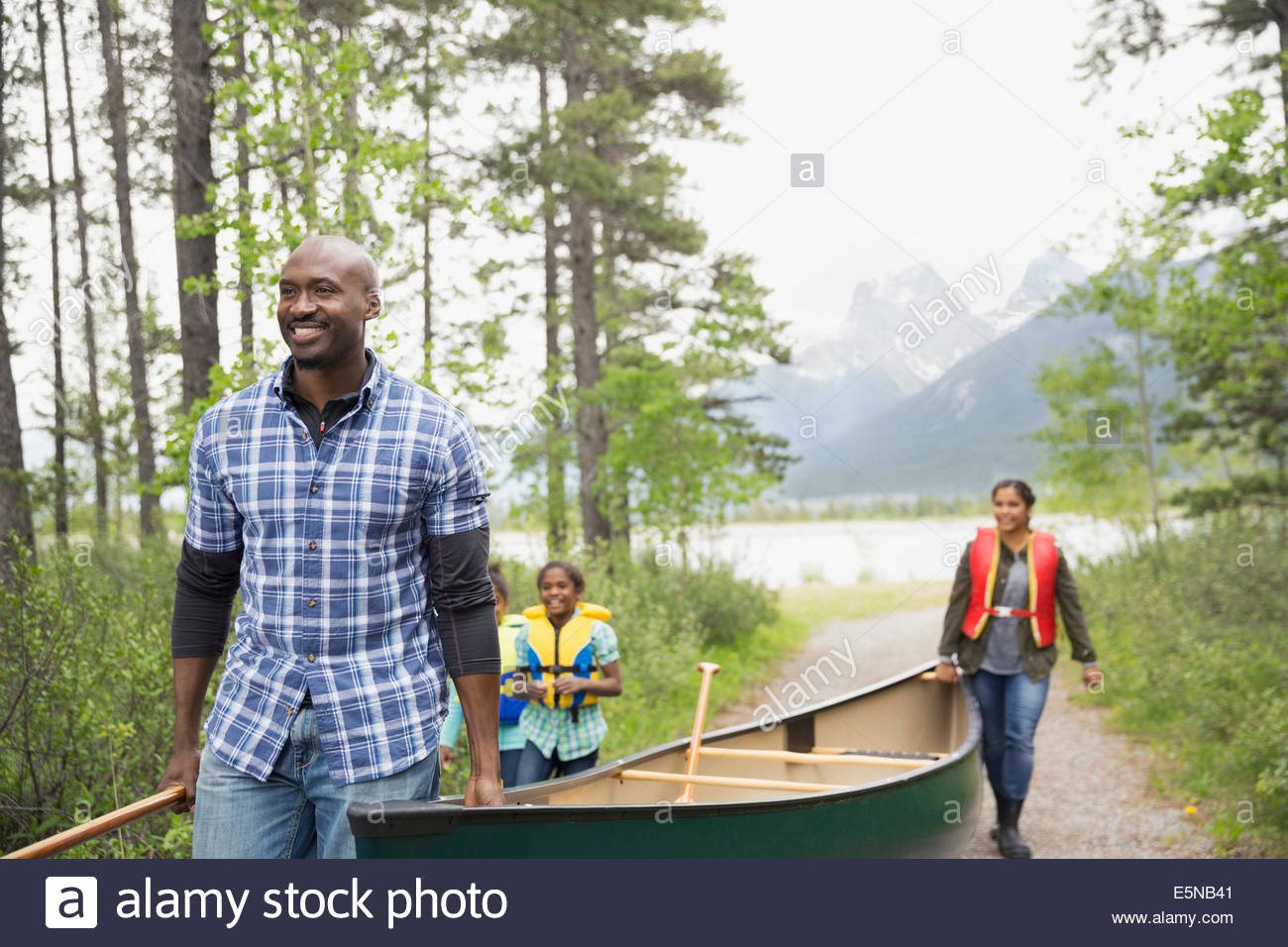 Family carrying canoe away from lake Stock Photo