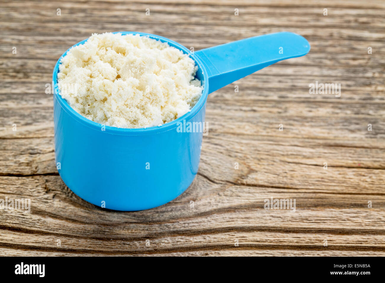 Whey Protein Powder In A Blue Plastic Measuring Scoop Against