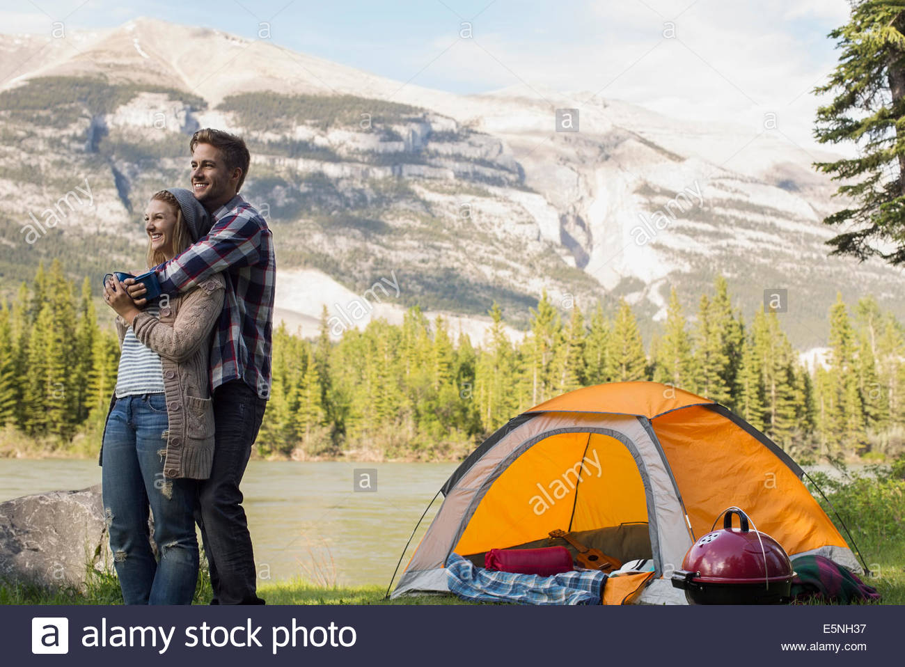 Couple hugging outside campsite at lakeside Stock Photo Alamy