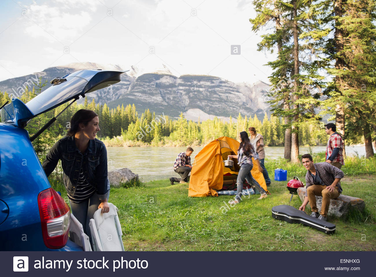 Friends assembling tent at campsite near mountains Stock Photo