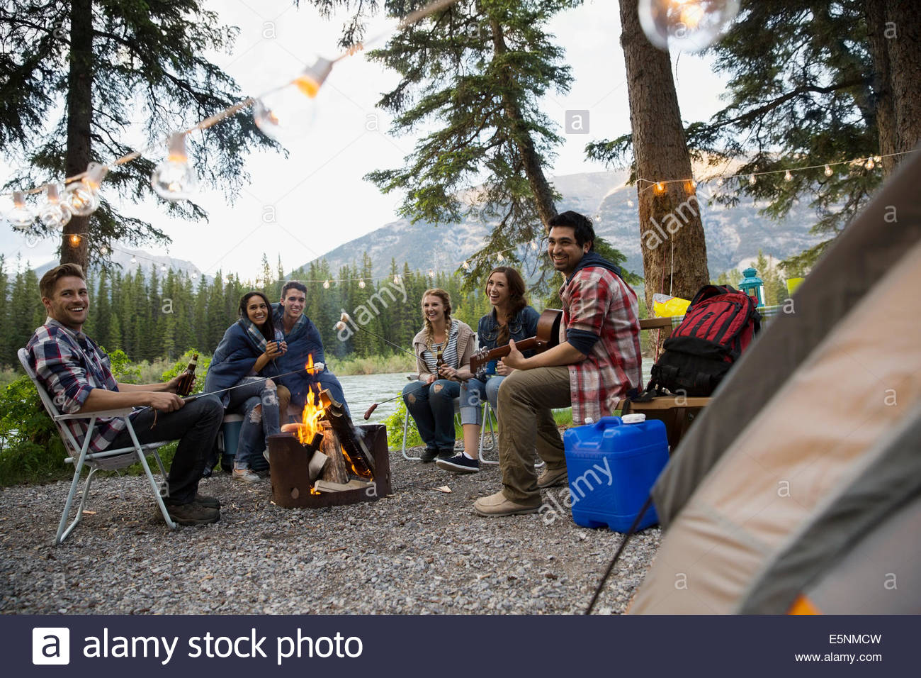 Friends hanging out around campfire at campsite Stock Photo