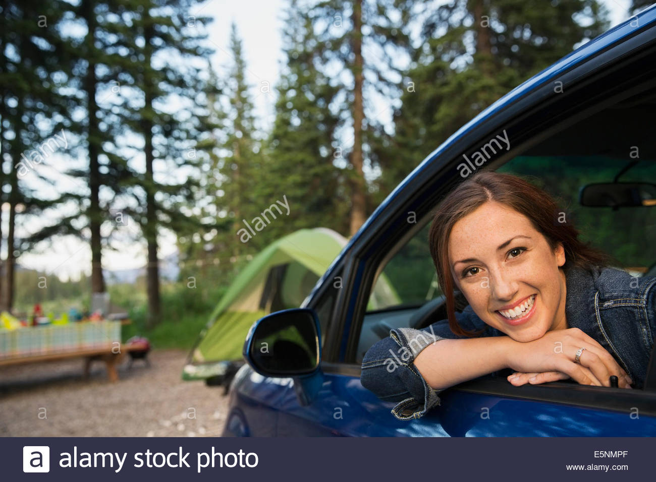 Smiling woman in car at campsite Stock Photo