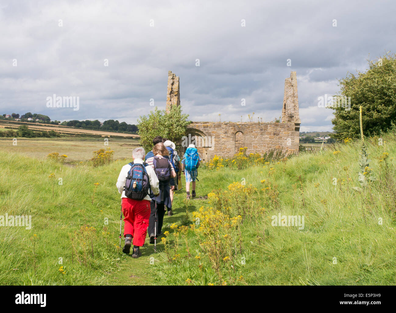 Walkers approaching the ruined chapel on Church Hill, Alnmouth, Northumberland, north east England, UK Stock Photo