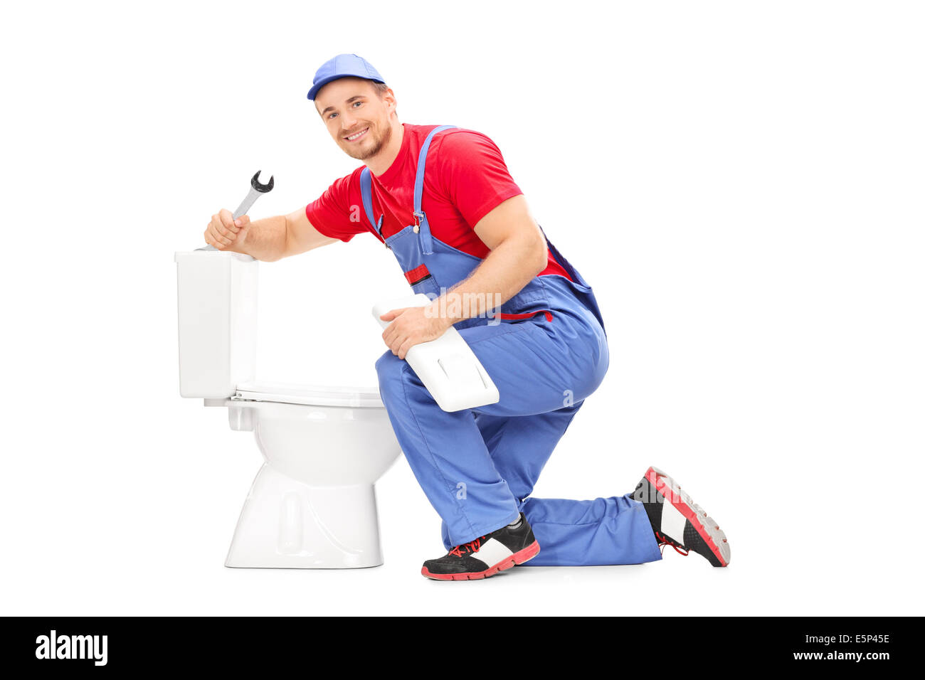 Smiling plumber trying to fix a toilet Stock Photo Alamy