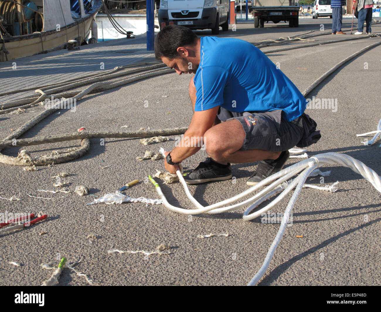 Fishermen in Mallorca splicing a rope together on the harbour or harbor ...