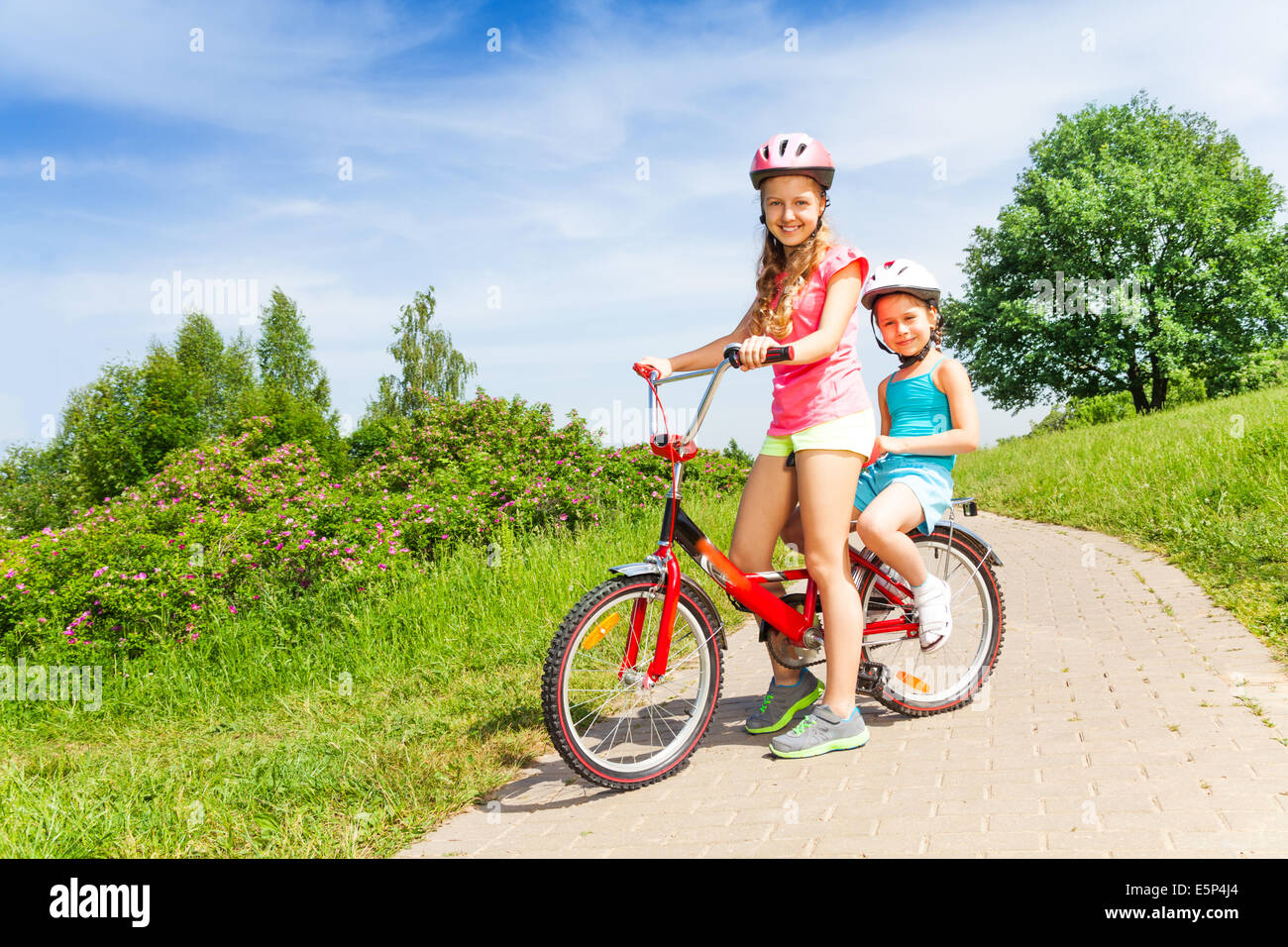 Two little girls sit on a bicycle Stock Photo