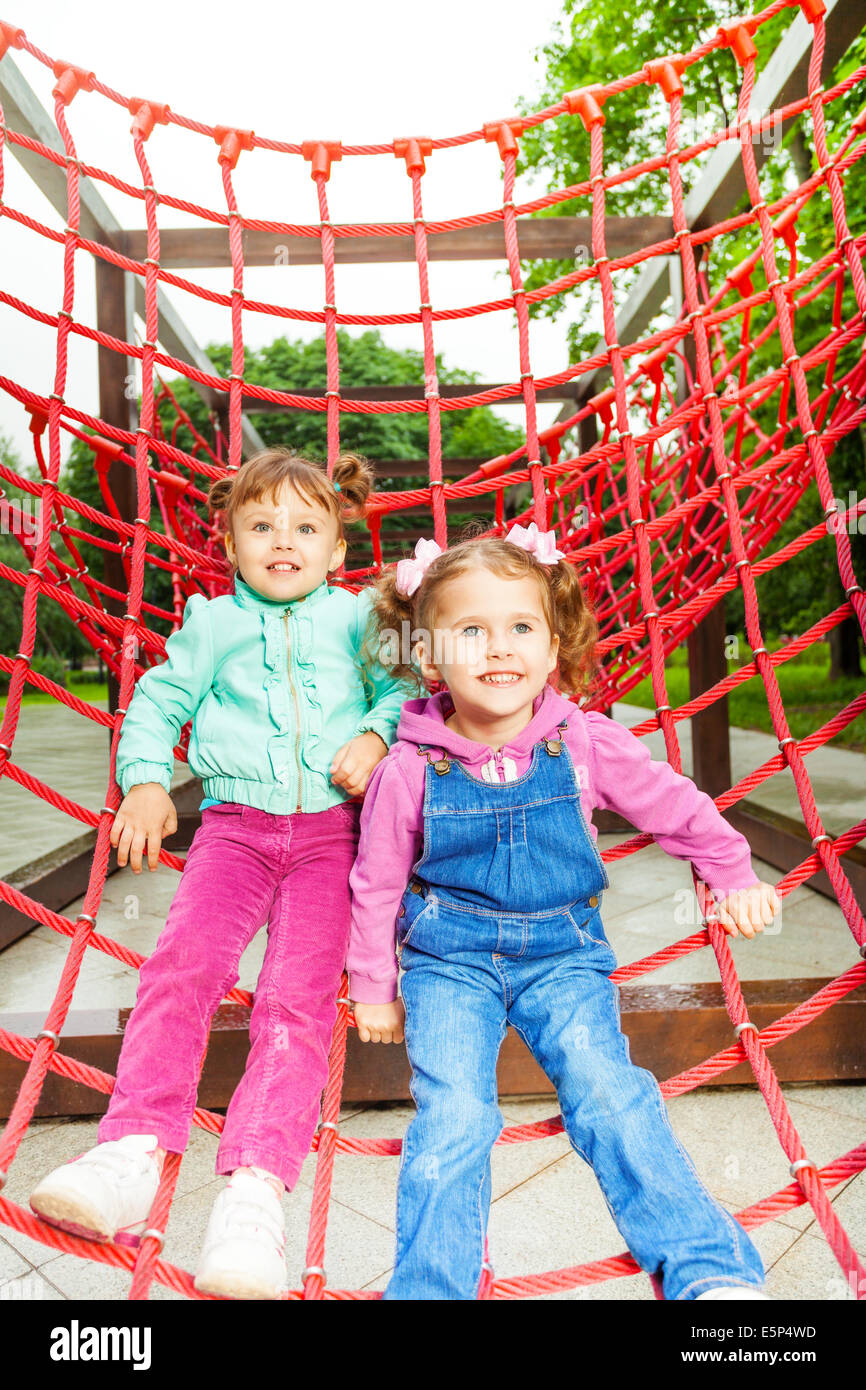 Two charming girls on net of playground Stock Photo - Alamy