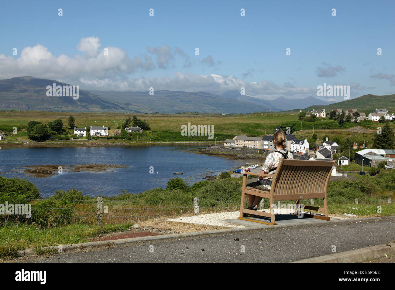 A lone woman sat on a bench admiring the view at Bunessan , Isle of Mull, Scotland, July 2014 Stock Photo