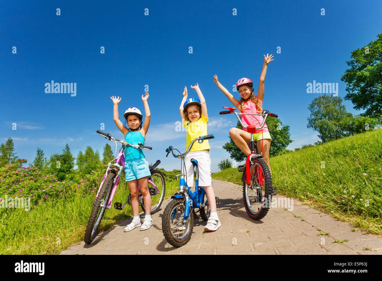 Three little girls on a bikes outsides Stock Photo