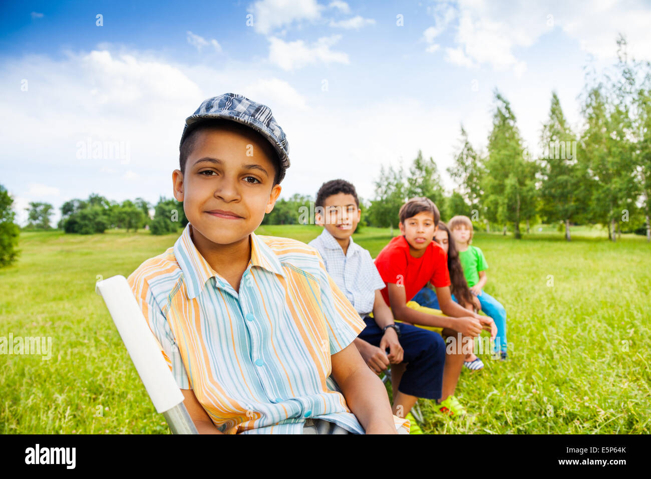 Five happy children sit on chairs in row outdoors Stock Photo - Alamy