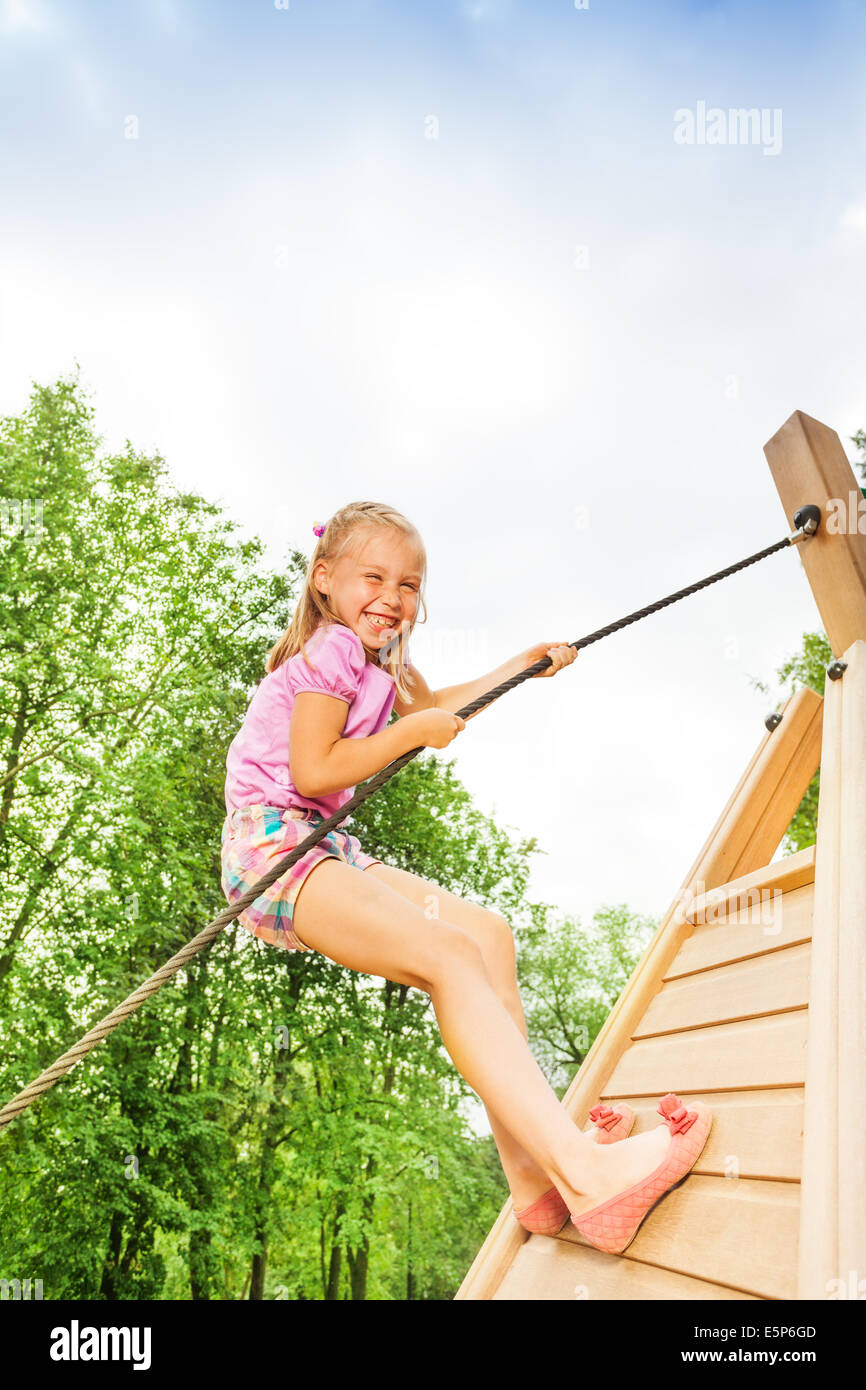 Smiling girl climbs on wooden construction Stock Photo