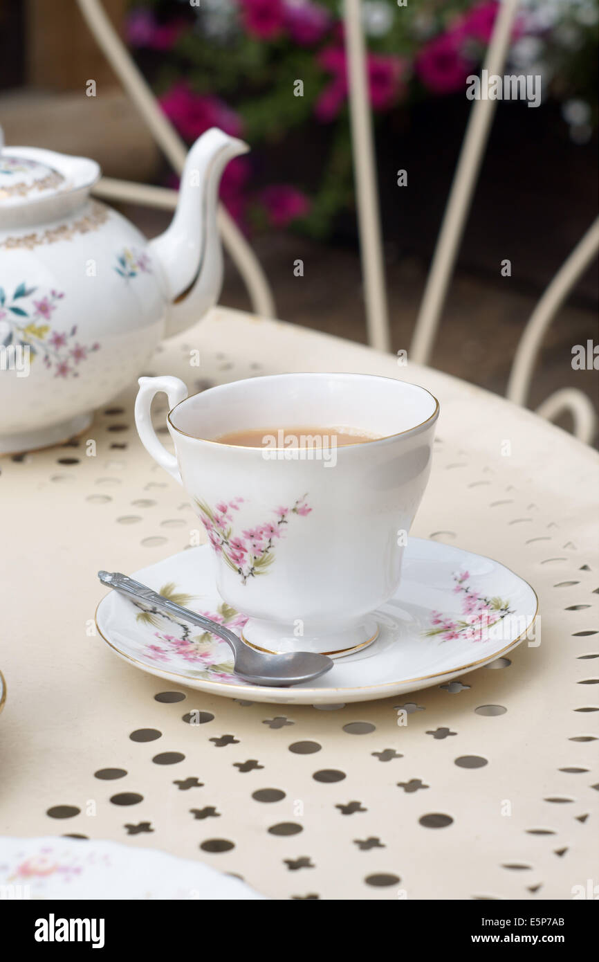 Afternoon tea served in vintage floral cups and saucers on a garden