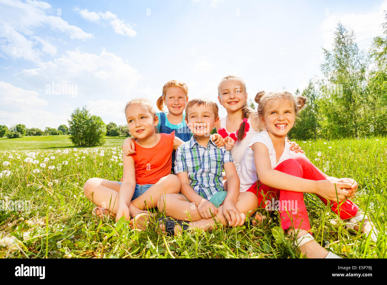 Five kids smile sitting on a grass Stock Photo - Alamy
