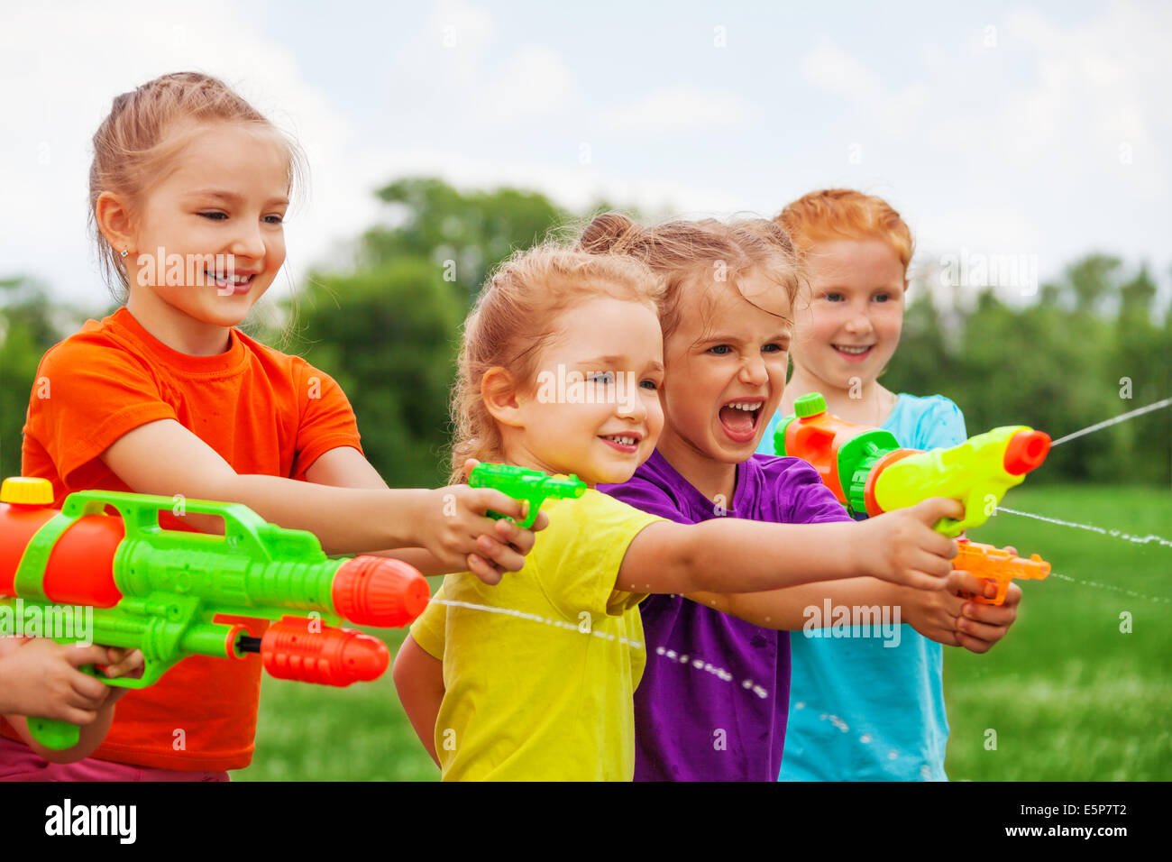 Kids play with water guns on a meadow Stock Photo