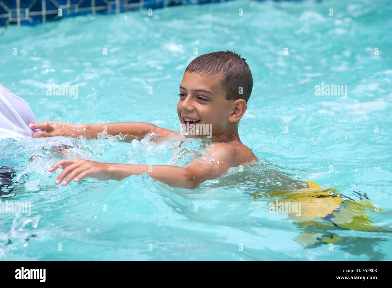 Young boy swimming and playing in a swimming pool Stock Photo