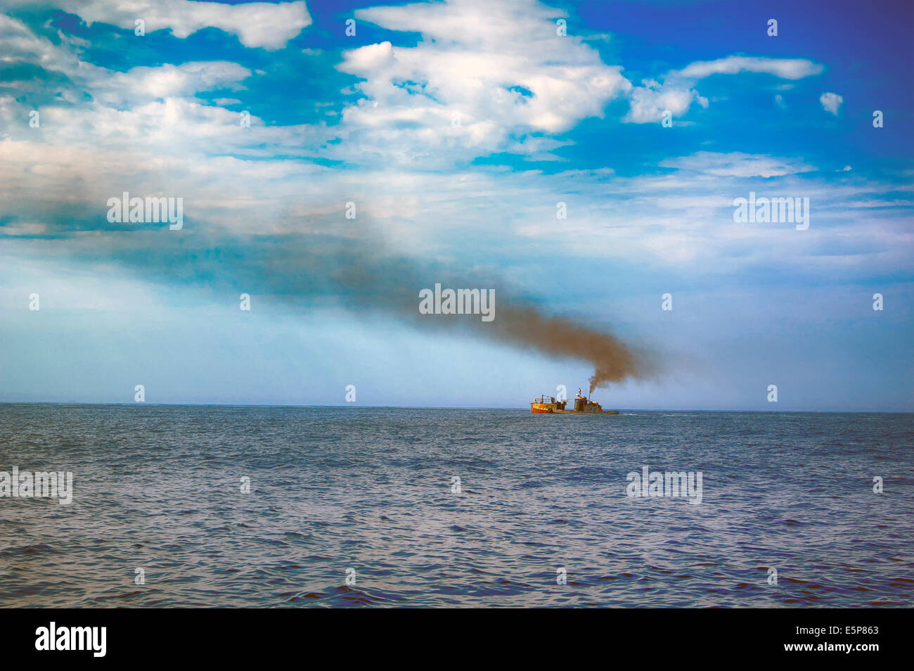 Ship in blue sea with dark smoke Stock Photo