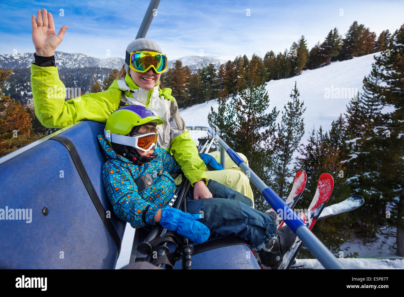 Happy mom and boy in ski masks seat on elevator Stock Photo