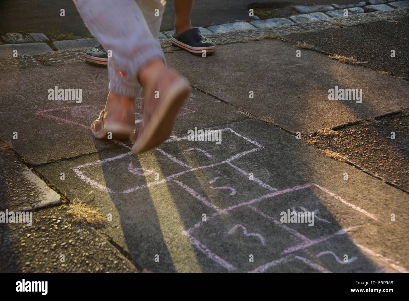 Child playing hopscotch on marked out chalk on a pavement, London, UK Stock Photo