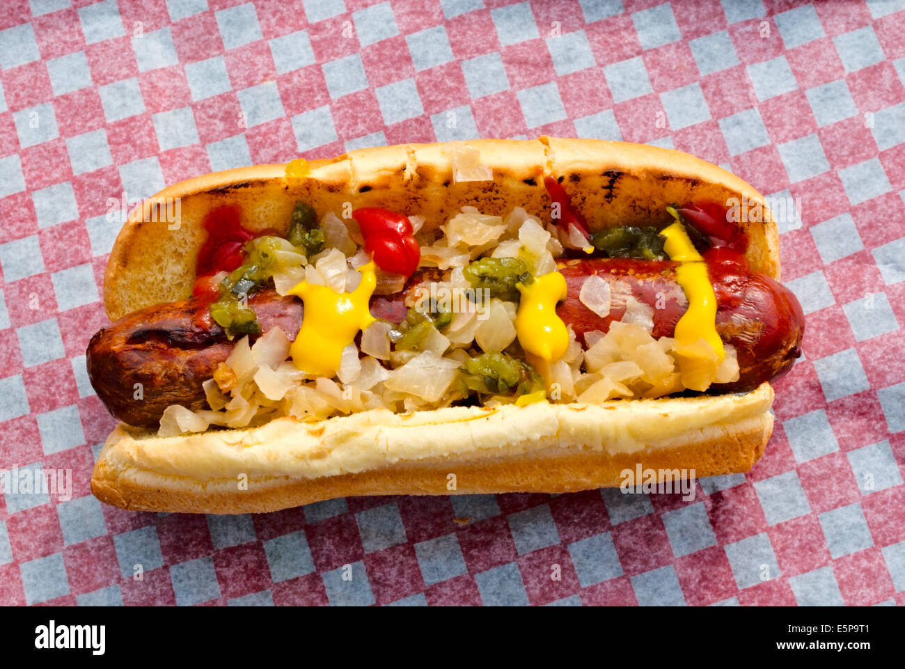 Sausage on a bun with onions, ketchup, mustard, and relish, on