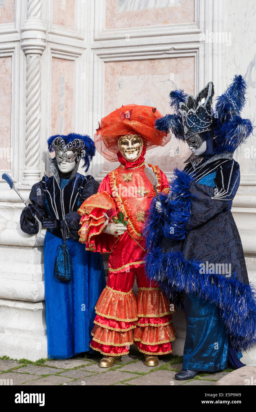 Women in elaborate blue & black costumes and brightly colored orange clown  in San Zaccaria Square during Carnival in Venice Stock Photo - Alamy