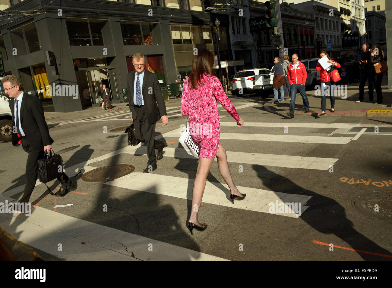 man watches woman cross street downtown san francisco Stock Photo